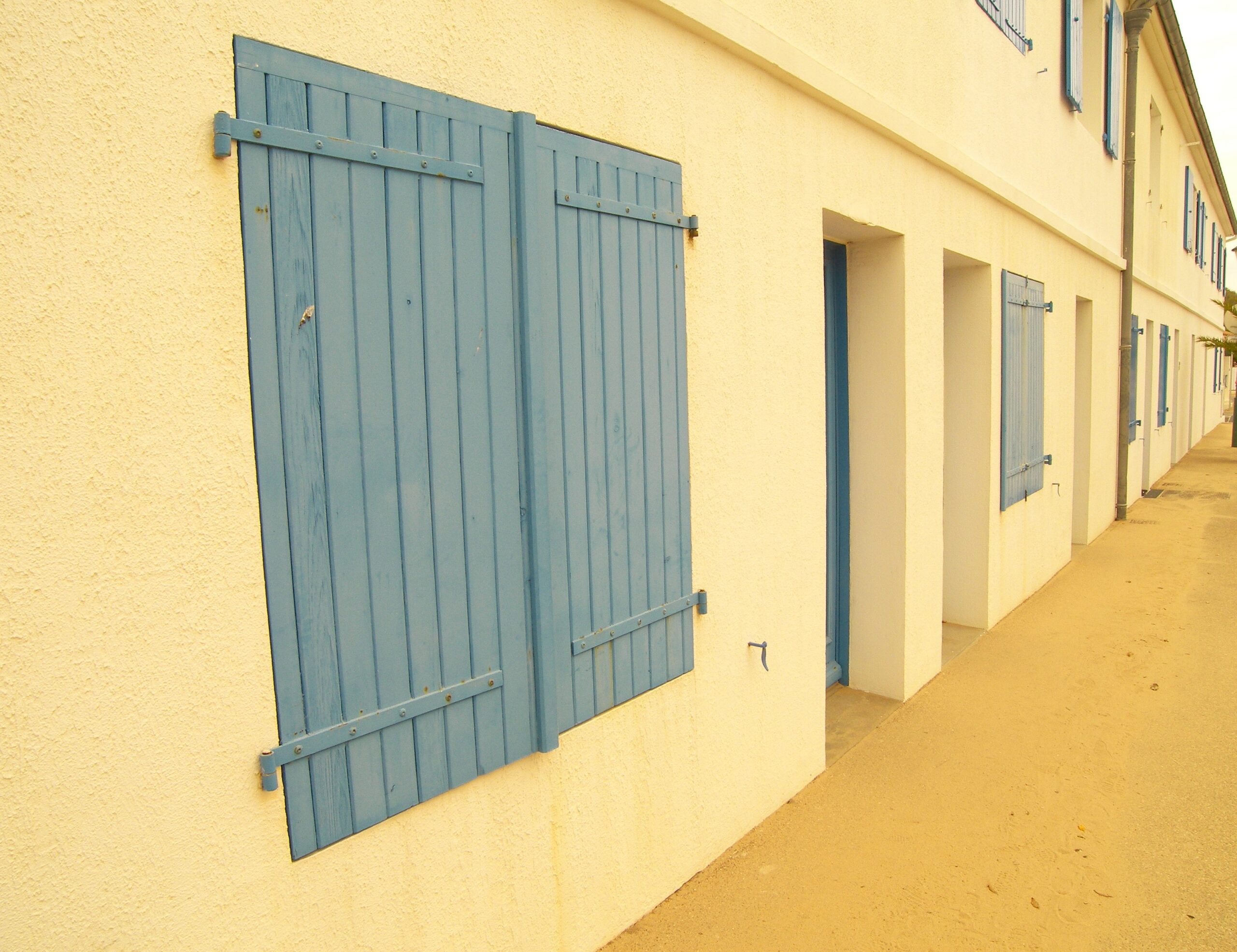 long-shot-yellow-building-facade-with-bluish-widows-doors